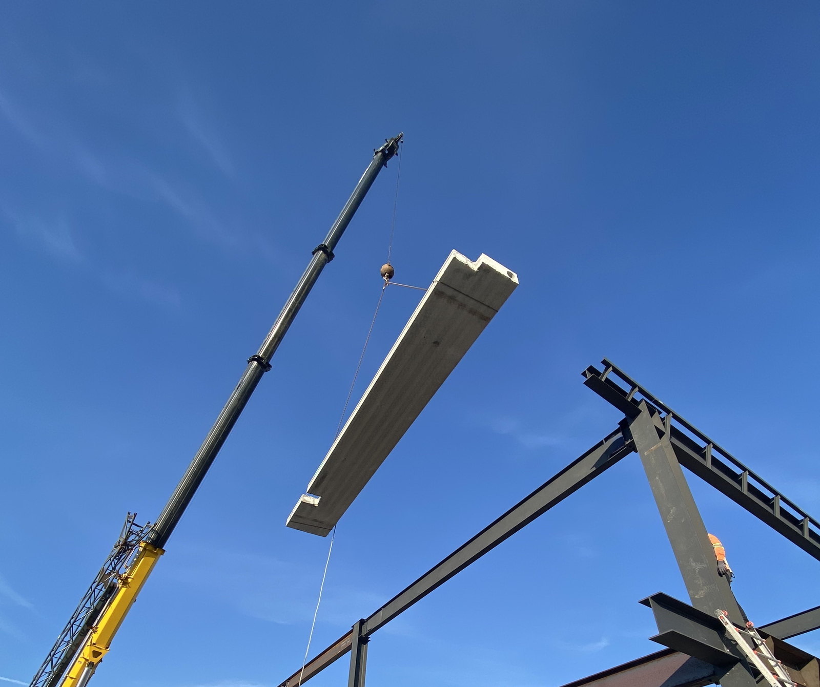 Crane lifting a precast concrete unit into the steel frame
