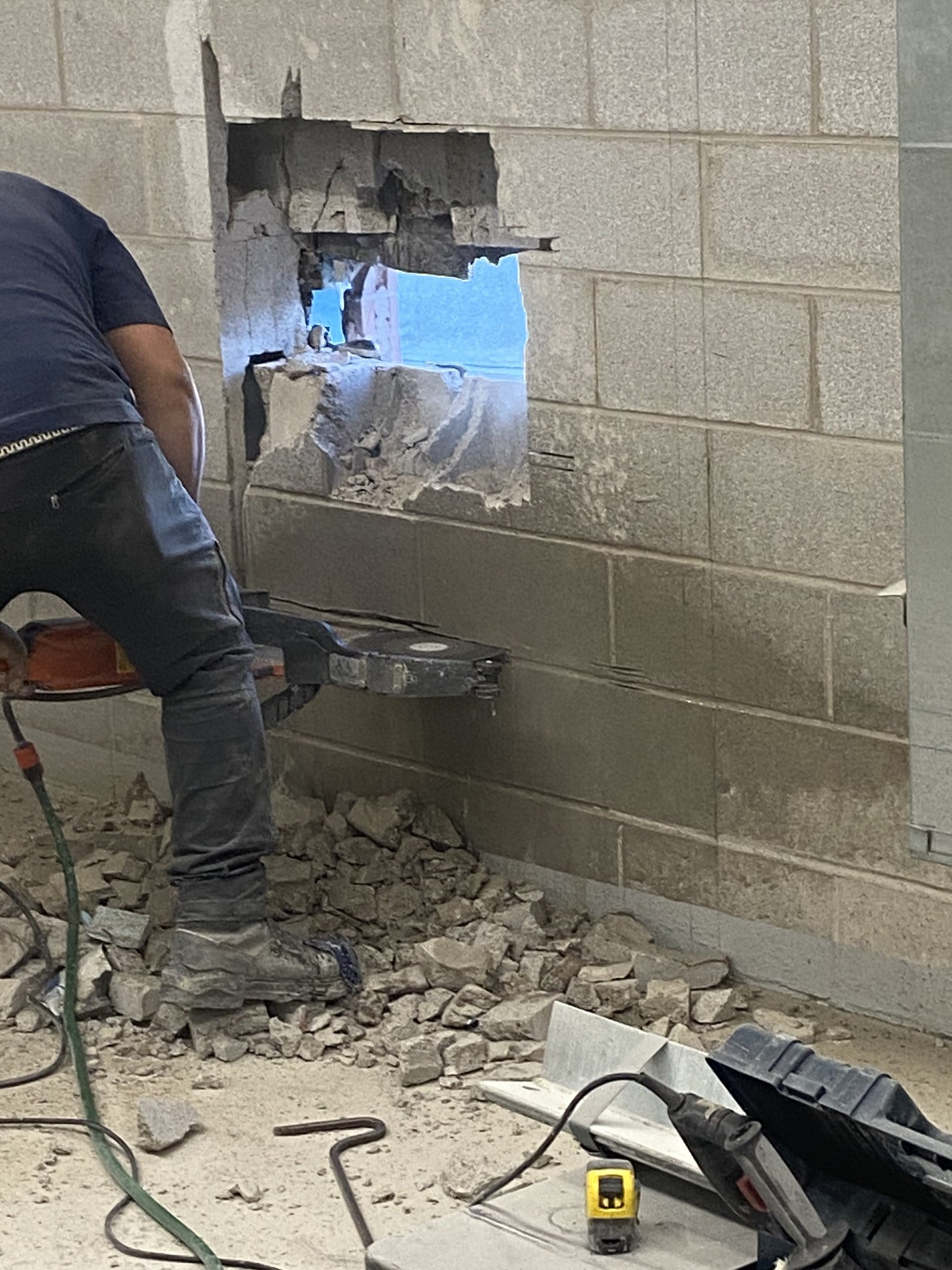 Worker cutting a new opening through an existing block wall
