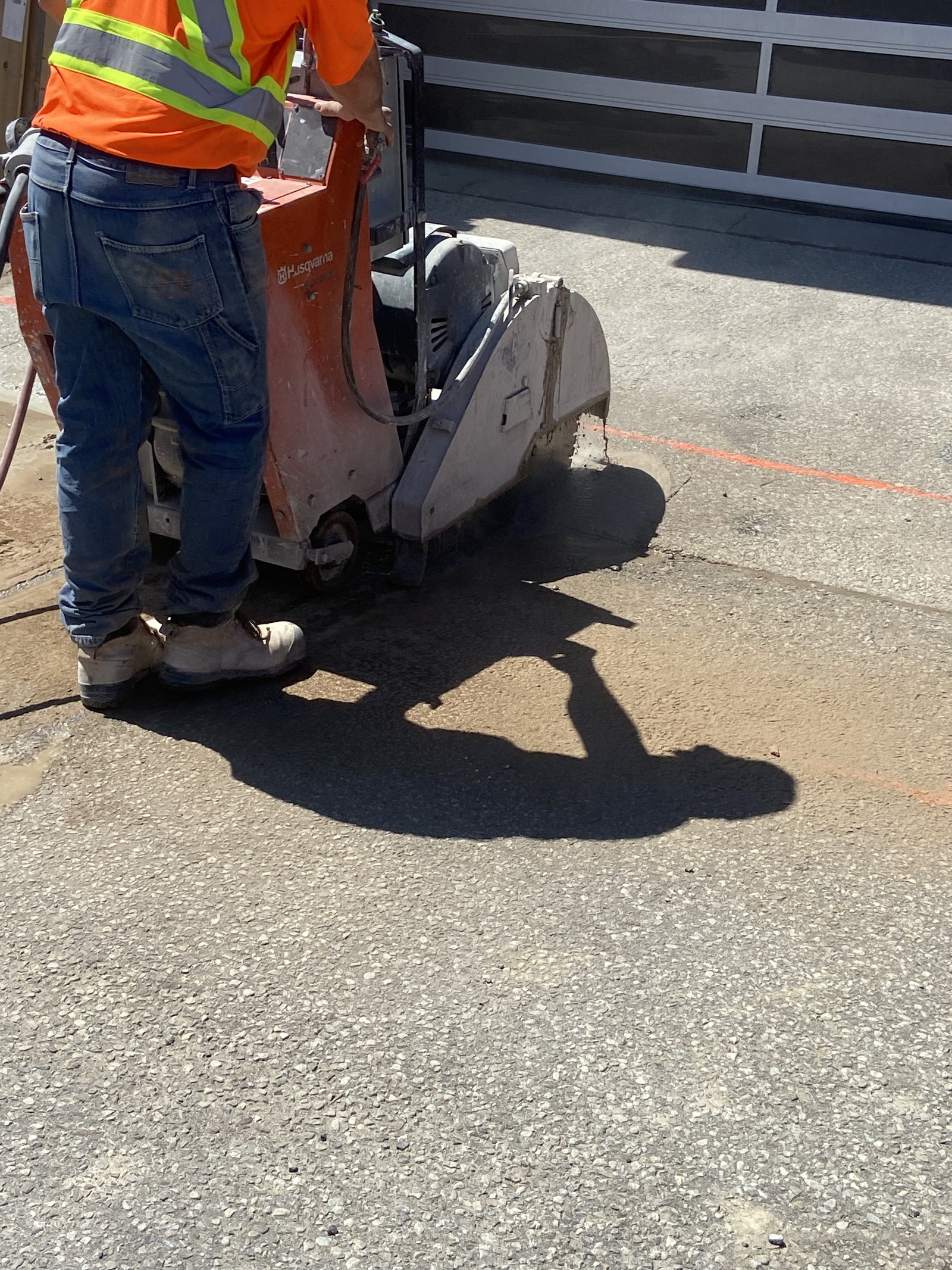 Worker saw-cutting the existing concrete apron
